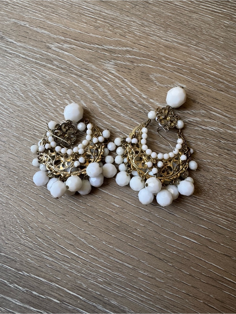 Gold tone dangle earrings with white dangle beads